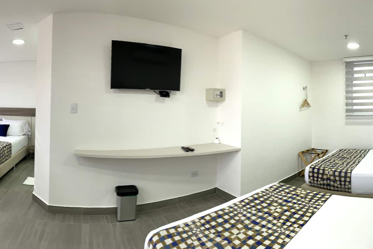 A hotel room with two beds, a TV, a small desk, and a trash bin.