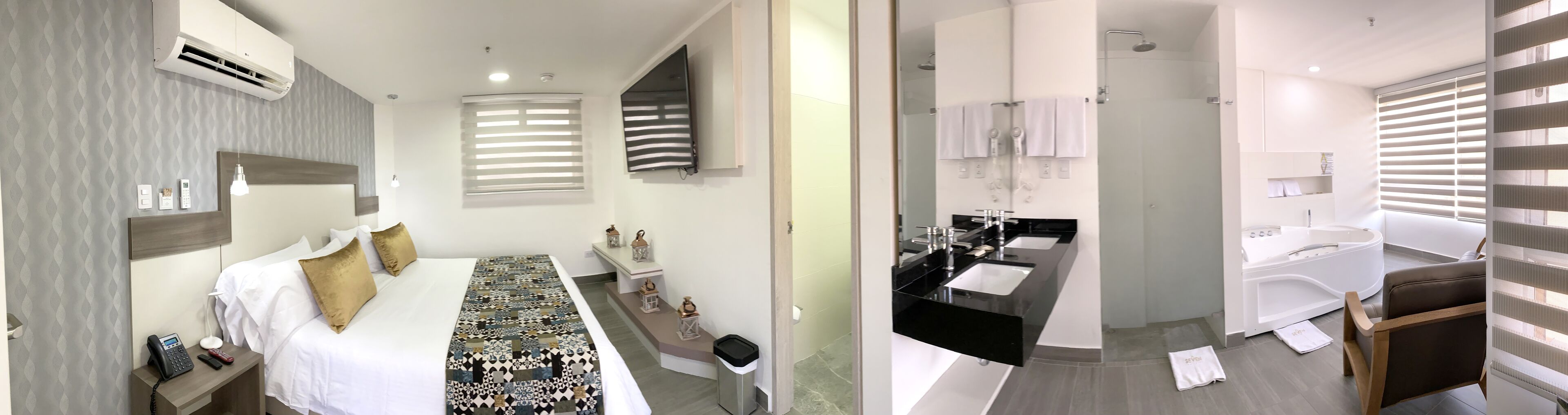 Una habitación de hotel moderna con una cama grande, teléfono junto a la cama y una lámpara de noche.