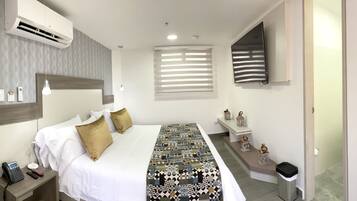 Una habitación de hotel moderna con una cama grande, teléfono junto a la cama y una lámpara de noche.