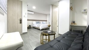 Ein modernes Hotelzimmer mit Bett, Sofa, kleinem Tisch und Schreibtisch.