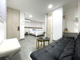 Una habitación de hotel moderna con cama, sofá, una mesita y escritorio.