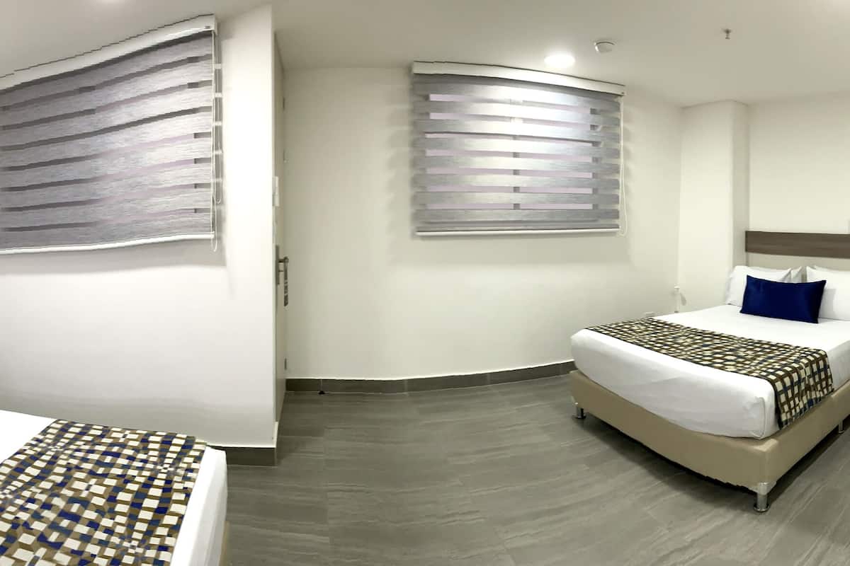 A hotel room with two beds, a phone, an air conditioner, and a window with blinds.