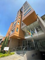 Un hotel moderno con un diseño arquitectónico único, destacando un amplio frente de vidrio y una escalera que conduce a la entrada.