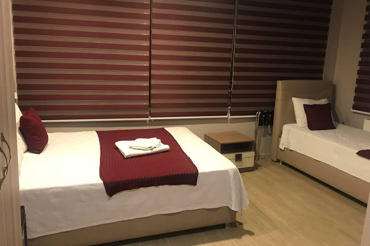 A hotel room with a bed, a nightstand, and a sofa.