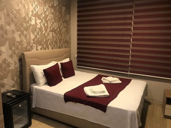 A neatly made bed with a headboard, two pillows, and a folded towel on a white bedspread. - Altinboynuz Family Hotel (Istanbul)