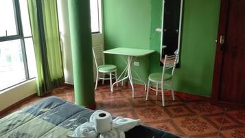 A room with a bed, a small table, two chairs, a window, and a door.