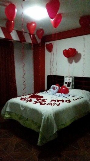 A room with a bed, red heart-shaped balloons, and a heart-shaped decoration on the bed. - Hostal El Parque (Huancayo)