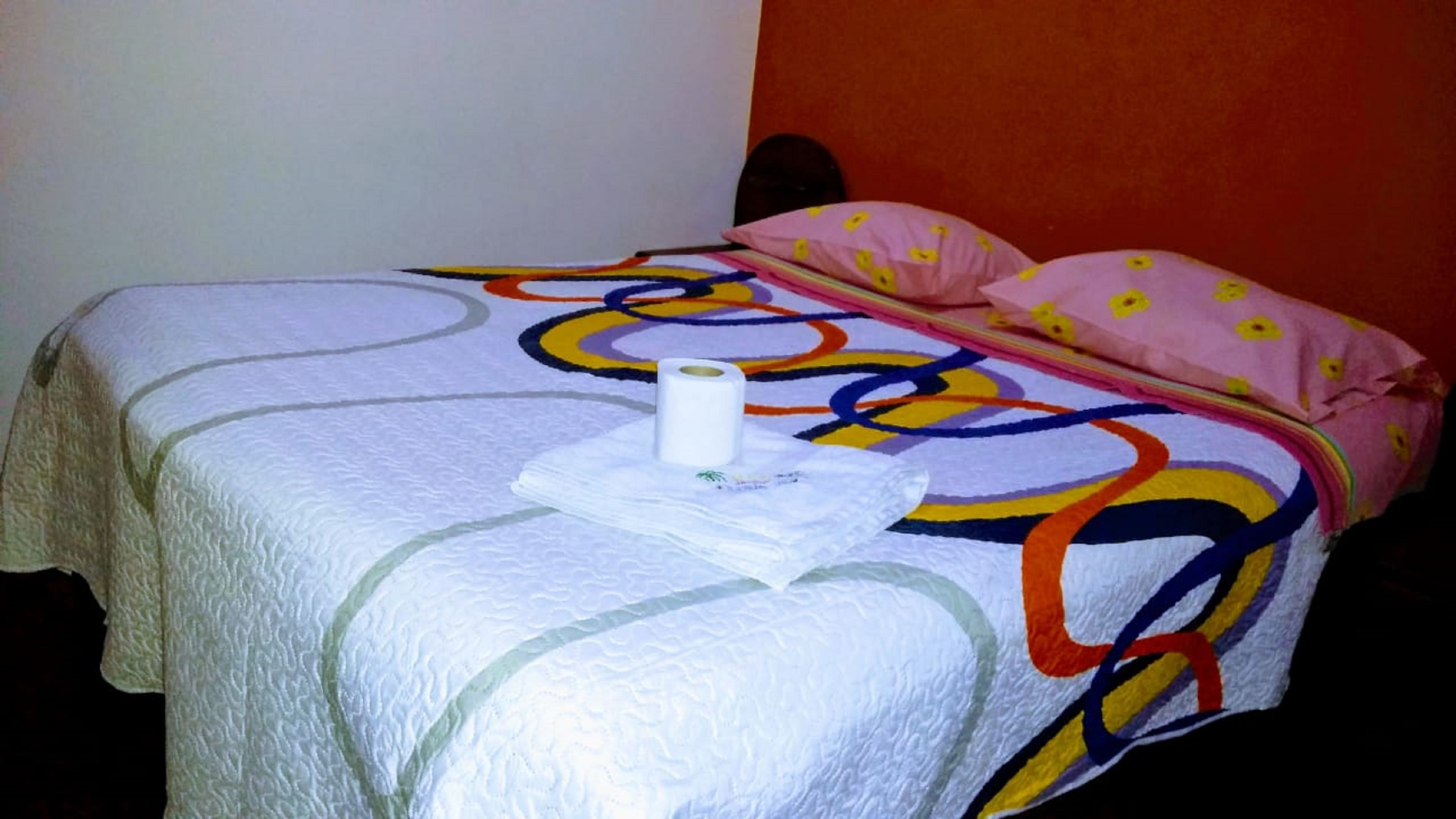 Un lit avec une couverture colorée et un rouleau de papier toilette.