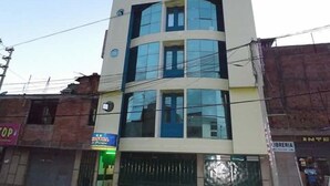 A multi-story building with a modern architectural design, featuring large windows and a flat roof. - Hostal El Parque (Huancayo)