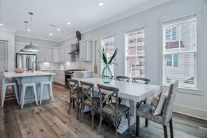 Una cocina moderna con una isla central, sillas de madera y una mesa de comedor.