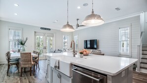 A modern kitchen with a large island, white cabinetry, and stainless steel appliances.