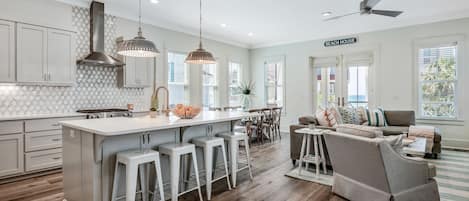 A modern kitchen with a large island, bar stools, and pendant lighting.