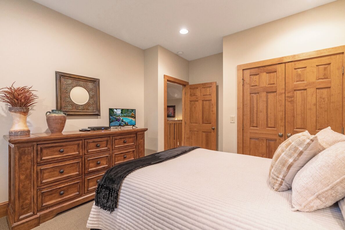 Ein Schlafzimmer mit einem Bett, einem Holzschrank und einer Tür zu einem anderen Raum.