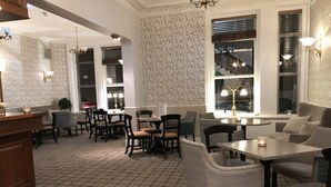 A dining area with checkered flooring, multiple tables and chairs, and decorative lighting. - The Clarendon Hotel (Morecambe)