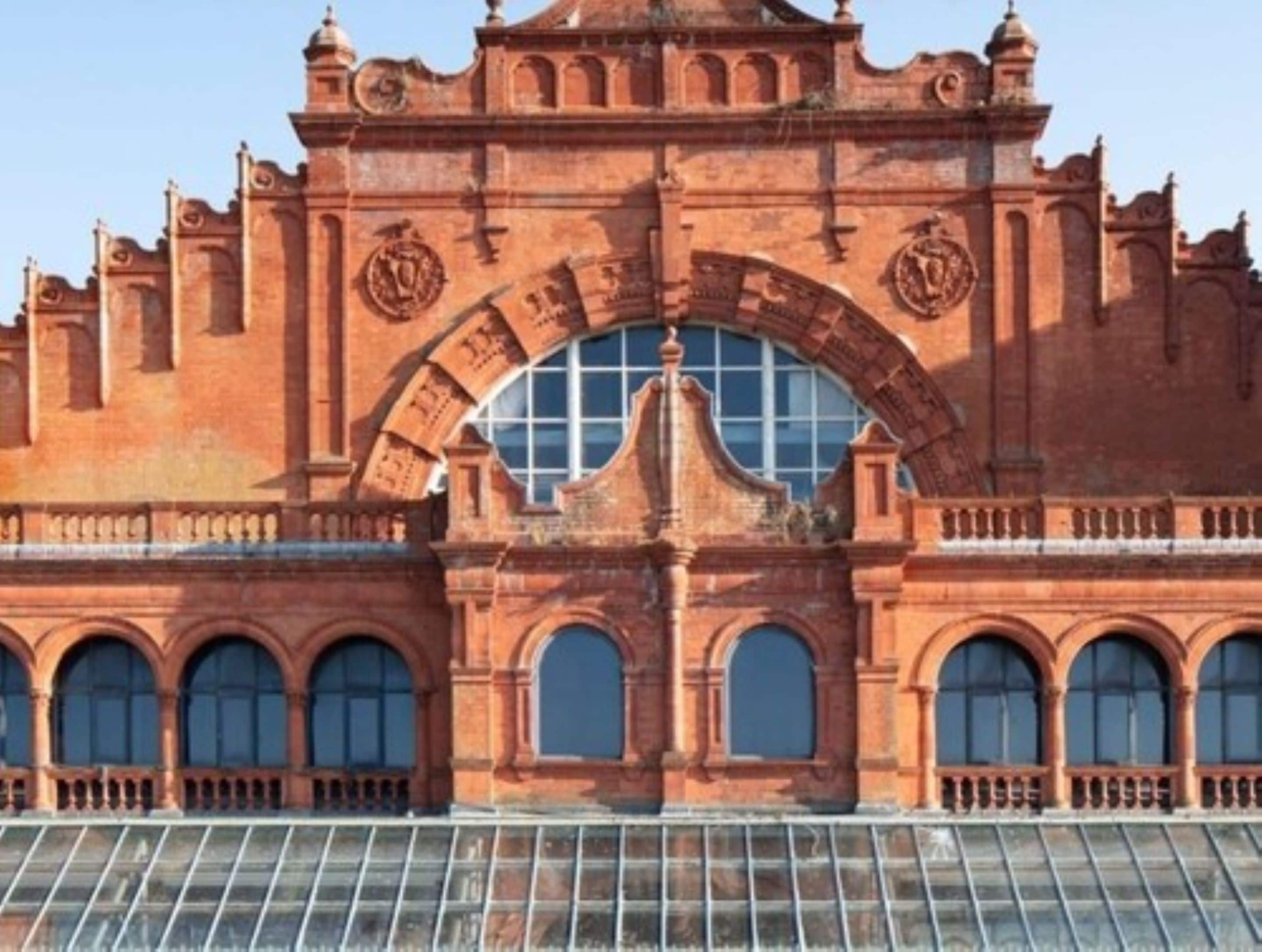A large, red-brick building with a central arched window and multiple smaller windows below.