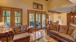 A spacious living room with a high ceiling, large windows, and a cozy fireplace. - A Foxfire Retreat: Gated Resort w/ Pools & Hot Tub, Fishing, Fitness Area (Boone)