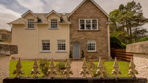 Une maison à deux étages avec une façade en pierre et un extérieur de couleur beige.