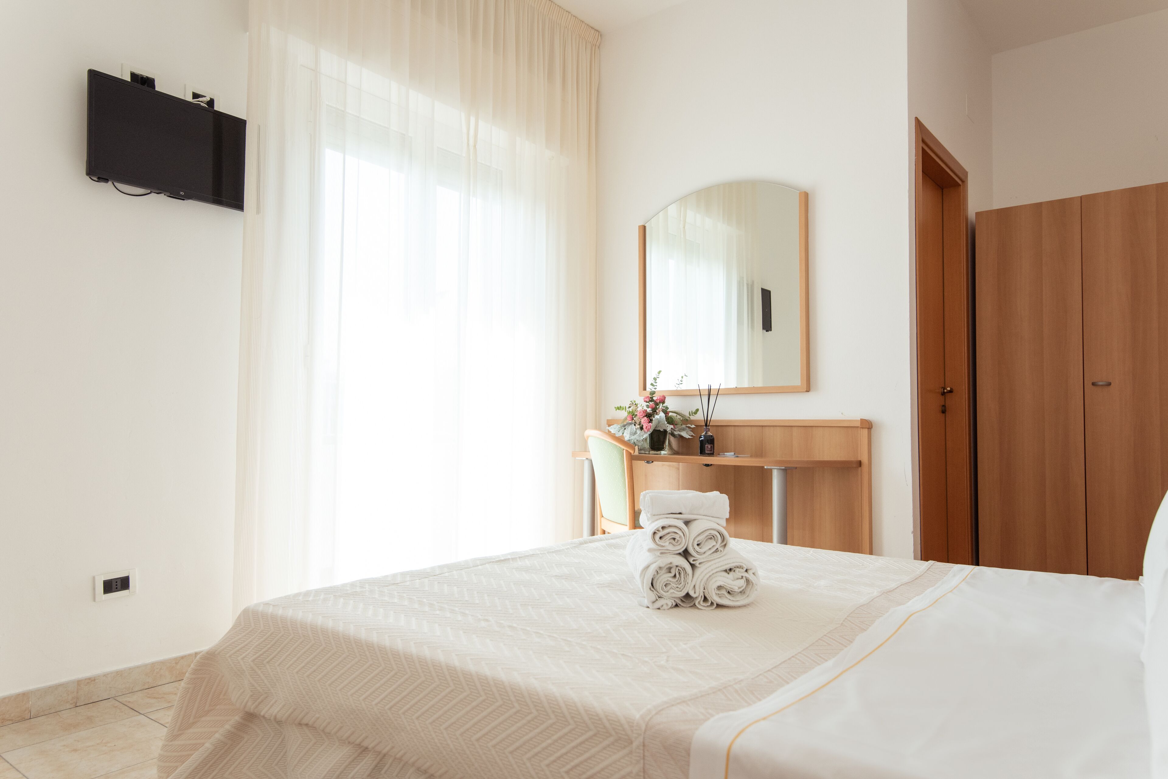 Una habitación de hotel con cama, escritorio, espejo y armario.