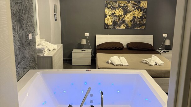 Een moderne slaapkamer met een vrijstaand bad, een bed met twee kussens, en een wandairconditioner.