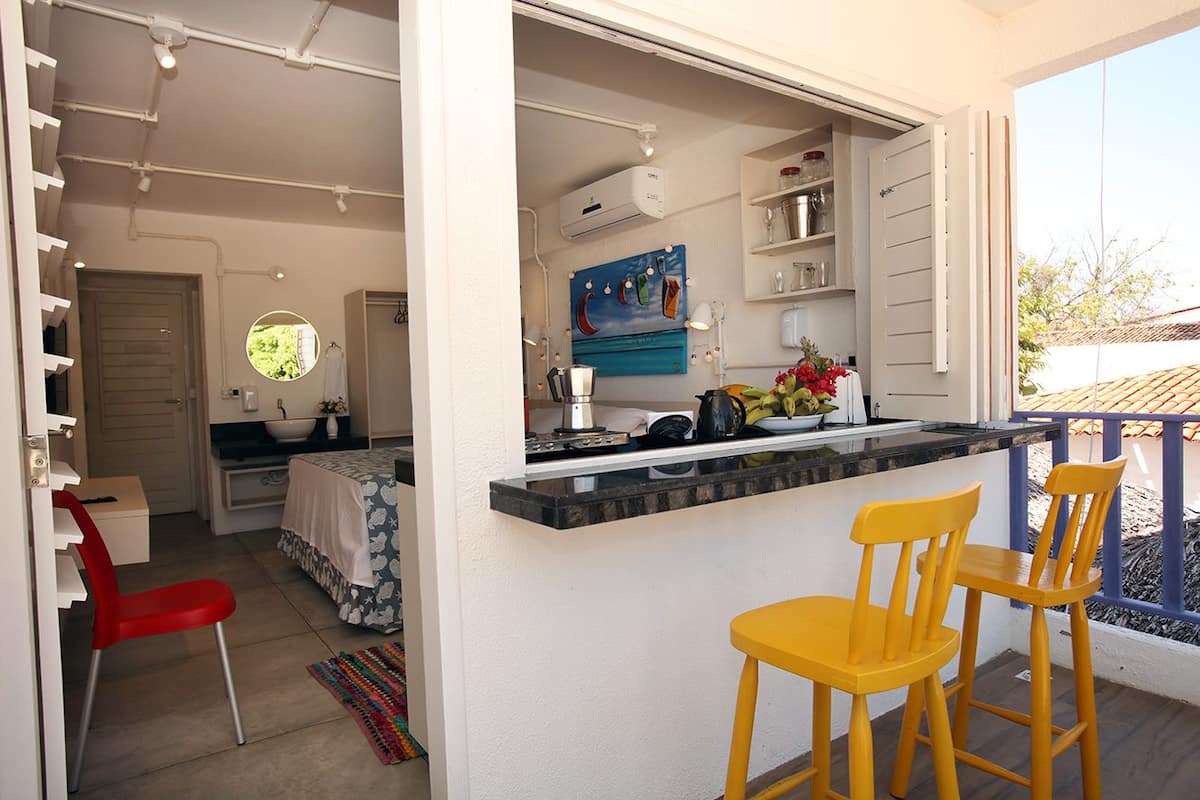 A compact kitchen with a bar area, a dining table with chairs, and a view of the outdoors.