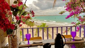 A balcony with a view of the beach and wind turbines, a vase with flowers, and a table with a coffee pot and cups. - Saint Germain Kite Residence (Amontada)