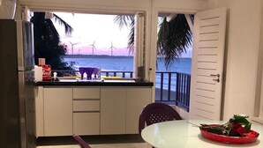 A compact kitchen with a view of the sea, a dining area with purple chairs, and a table with a red bowl. - Saint Germain Kite Residence (Amontada)