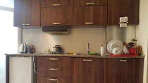 Une cuisine moderne avec des meubles en bois, une cuisinière encastrée et un réfrigérateur compact.