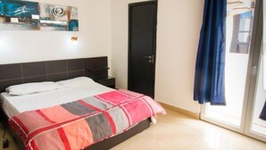 Une chambre à coucher avec un lit, une table de chevet, une porte et une fenêtre avec des rideaux.