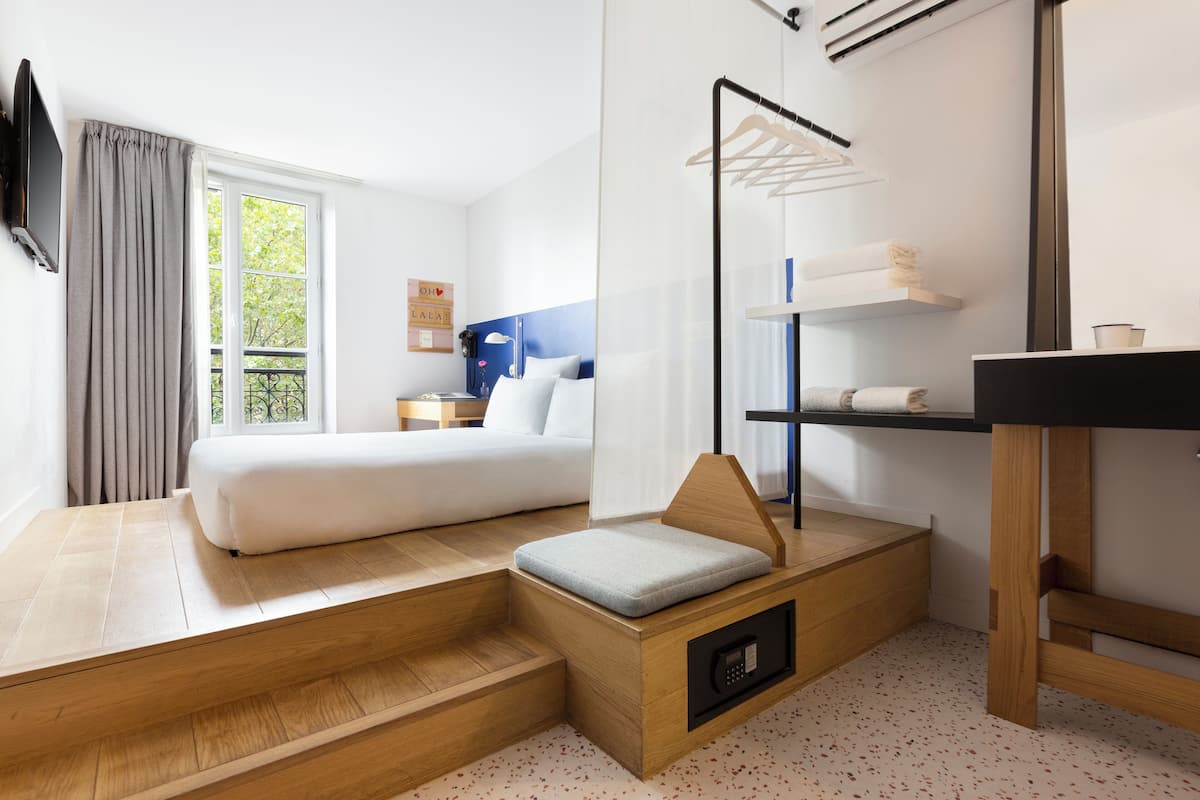 Una habitación de hotel moderna con una cama, un área de descanso, un escritorio y un televisor.