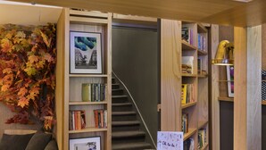 Eine gemütliche Leseecke mit Bücherregal, gerahmtem Bild und kleinem Tisch mit Kerze.