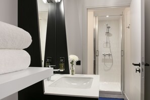 A modern bathroom with a white sink, a large mirror, a shower with a glass door, and a towel rack. - Oh La La! Hotel bar - Paris Bastille (Paris)