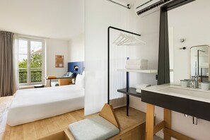 A hotel room with a bed, a desk, a chair, a bathroom with a mirror, and a window with curtains. - Oh La La! Hotel bar - Paris Bastille (Paris)