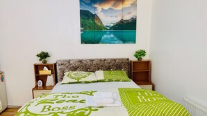 Un dormitorio ordenado con una cama, dos mesitas de noche, un cabecero y un cuadro colgado en la pared de un lago.