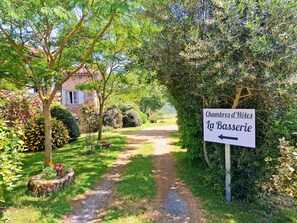 Señalización para 'Chambres d'Hotes La Basserie' con un sendero que lleva a un edificio de piedra.