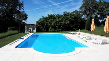 Una piscina al aire libre de temporada, sombrillas, tumbonas