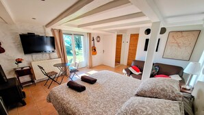 A hotel room with a large bed, a TV, a guitar, and a view of the outdoors. - La Basserie (Laguepie)