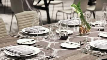 A dining table set with plates, cutlery, and glasses, with a vase of flowers and a candle holder.