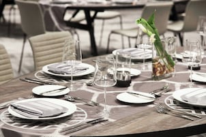 Una mesa de comedor dispuesta con platos, cubiertos y copas, con un jarrón de flores y un candelabro.
