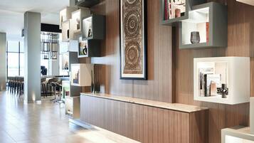A modern reception area with a wooden reception desk, built-in shelving with books and decorative items, and a large wall-mounted artwork.