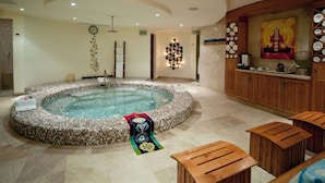A spa area with a hot tub, wooden seating, a clock, and a decorative wall piece. - PARTY on Cabo Villas & Mango Deck Executive Suite (El Medano)