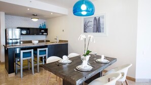 A modern kitchen with a built-in microwave, a stainless steel refrigerator, and a blue pendant light. - PARTY on Cabo Villas & Mango Deck Executive Suite (El Medano)