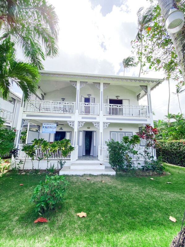 A two-story building with a balcony, a signboard, and a well-maintained lawn.