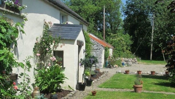 A house with a garden, a stone wall, and a gravel path. - 300 Year old Tradition Irish Cottage (Rathkeale)
