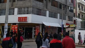 Un edificio de varios pisos con una planta baja comercial que alberga un restaurante con un letrero rojo.