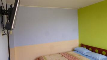 A bedroom with a bed, a television mounted on the wall, and a ceiling light.