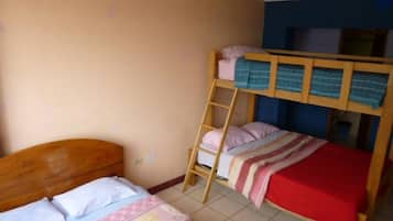 A dormitory room with bunk beds, a wooden ladder, and a tiled floor.