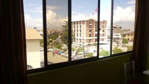 Una habitación con un amplio ventanal que da a una vista panorámica de la ciudad, incluyendo un edificio destacado con una bandera.