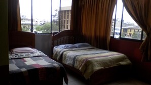 Una habitación con dos camas individuales, una ventana con cortinas y vistas a edificios.