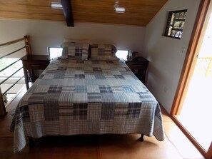 Relax in this serene bedroom with a large bed and a view of lush greenery outside.