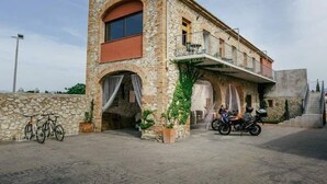 A stone building with a balcony, bicycles, and a motorcycle parked outside. - Cortijo Cal Rajoler (Cabanes)
